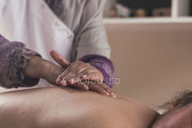 Terapeuta haciendo masaje oriental a mujer en sala de masajes - foto de stock