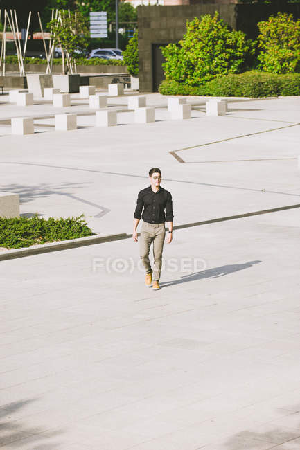 Selbstbewusster Mann mit Sonnenbrille und schwarzem Hemd läuft auf der Straße — Stockfoto