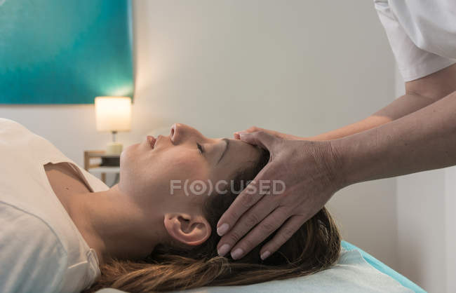 Terapeuta massageando a cabeça feminina na sala de massagem — Fotografia de Stock