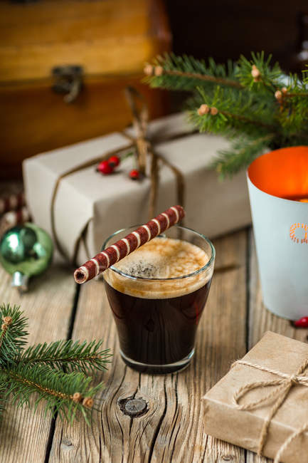 Glass of coffee with traditional Christmas roll tube pastry on wooden table — Stock Photo