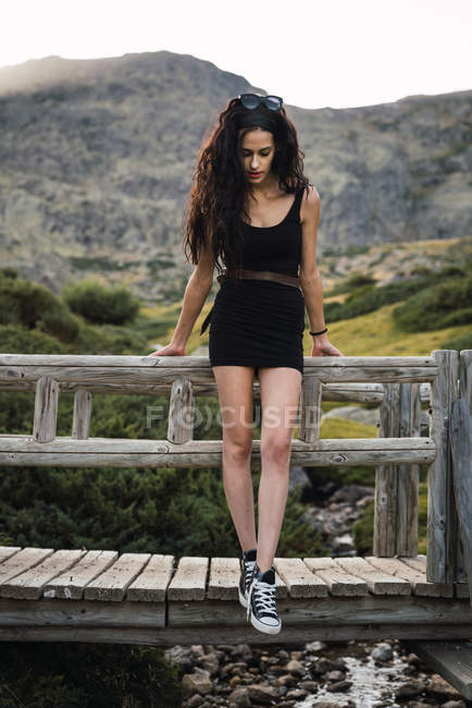 Schlanke Frau lehnt an Zaun über Tal in Bergen — Stockfoto
