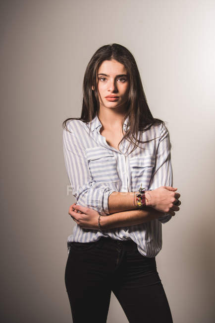 Young woman in shirt and jeans posing on grey background — Stock Photo