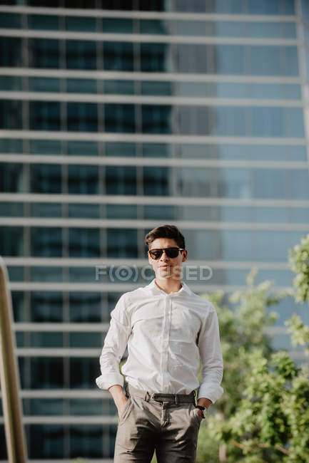 Confident young businessman standing in front of modern building — Stock Photo