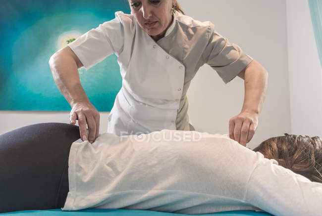 Terapeuta massaggio femminile di nuovo sul tavolo in sala massaggi — Foto stock