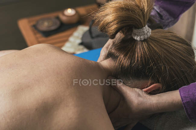 Terapeuta masajeando cuello femenino en sala de masajes - foto de stock