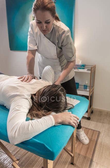 Therapist massaging female back on table in massage room — Stock Photo