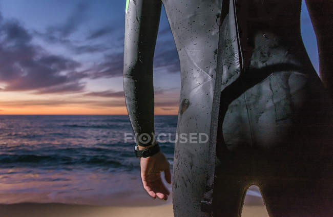 Triathlete wearing neoprene costume standing on beach at dawn — Stock Photo