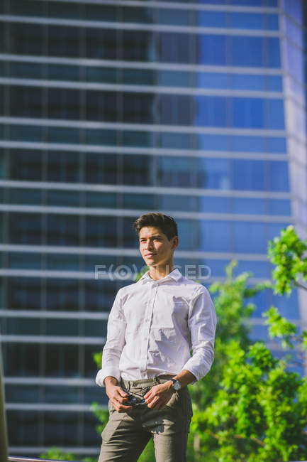 Fiducioso giovane uomo d'affari in piedi contro edificio moderno — Foto stock