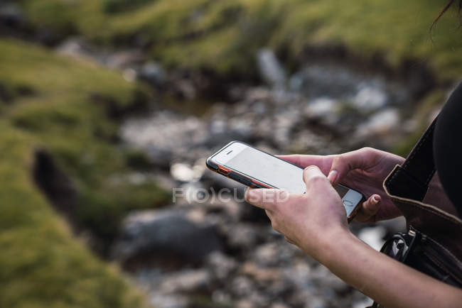 Hands of woman using smartphone in nature — Stock Photo