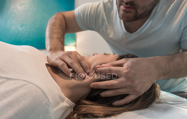 Therapist massaging female face in massage room — Stock Photo