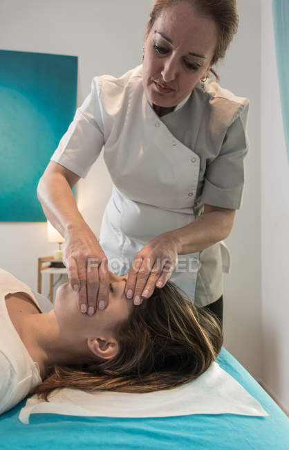 Therapeut massiert weibliches Gesicht im Massageraum — Stockfoto