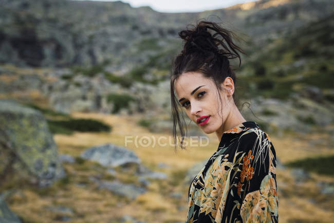 Случайная женщина в красочной рубашке, смотрящая в камеру в горах — стоковое фото