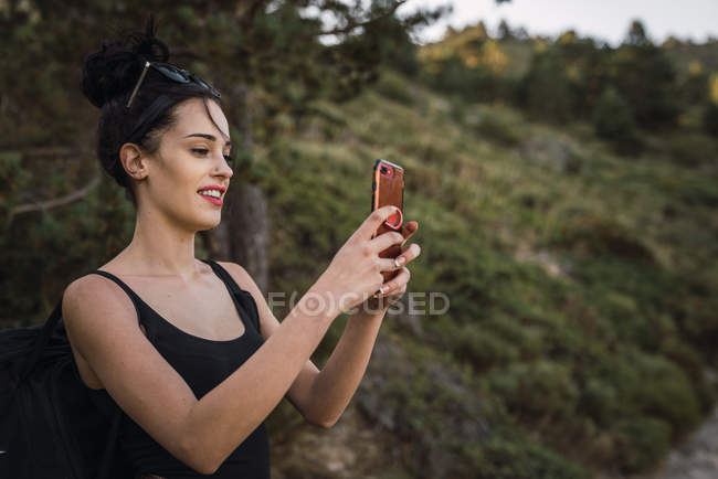 Junge hübsche Frau mit Rucksack fotografiert die Natur — Stockfoto
