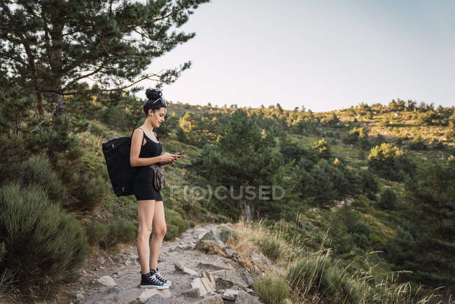Молодая красивая женщина с рюкзаком фотографирует природу — стоковое фото