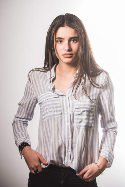 Молодая женщина в полосатой рубашке позирует на сером фоне — стоковое фото