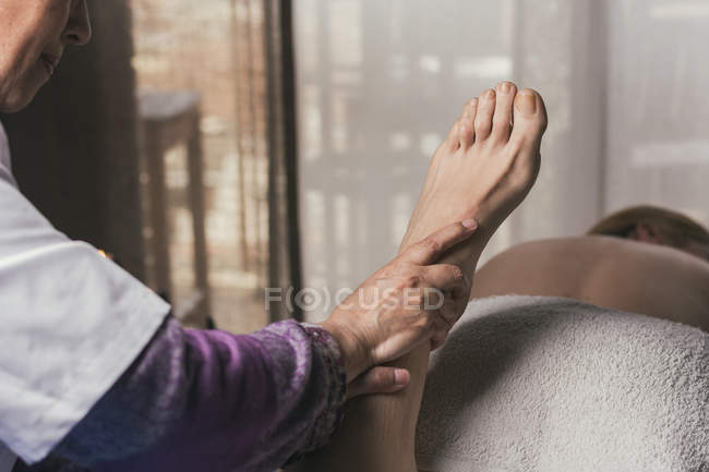 Therapist doing foot reflexology massage on female patient — Stock Photo