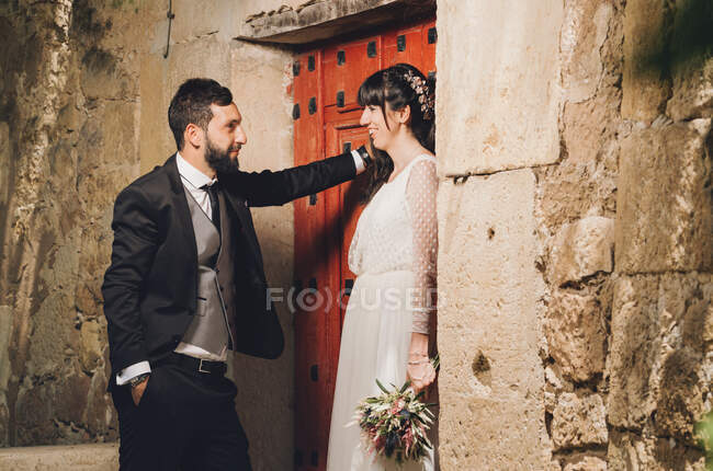 Young bride and groom standing together near wall — Stock Photo
