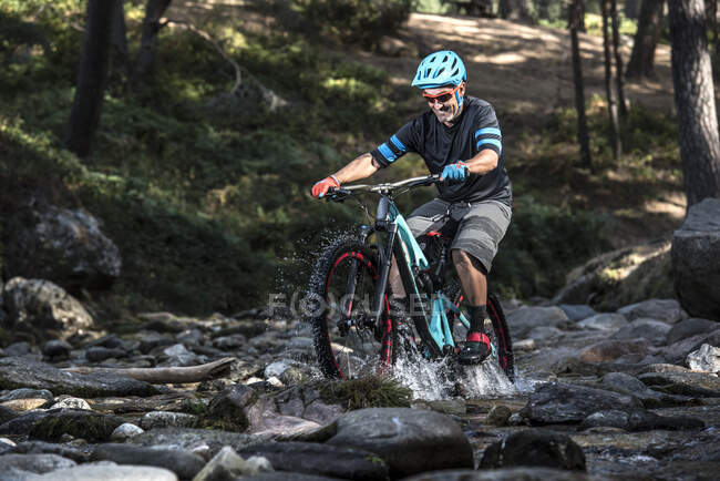 Motociclista in bicicletta su un fiume — Foto stock