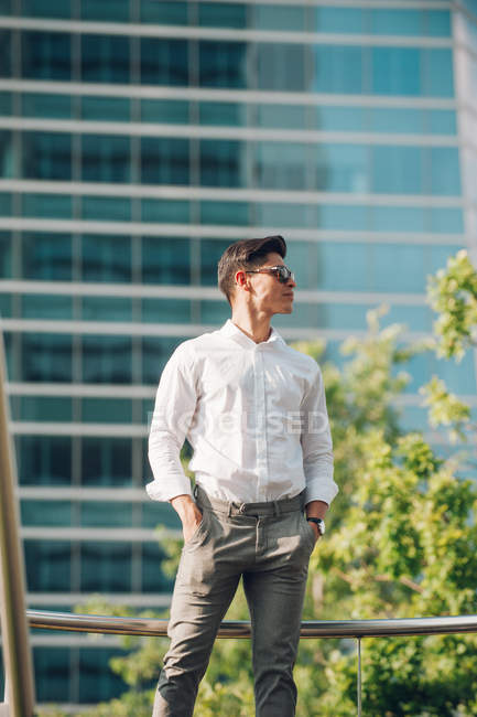 Уверенный в себе молодой бизнесмен, стоящий против современного здания — стоковое фото