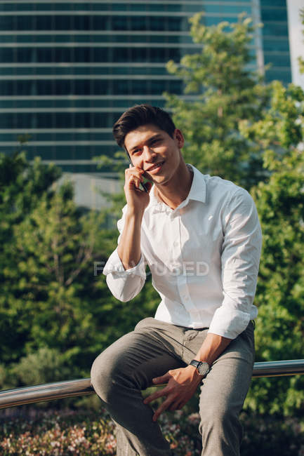 Молодий елегантний бізнесмен розмовляє по телефону на перилах на відкритому повітрі — стокове фото