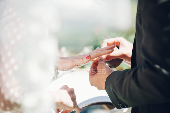 Joven hombre y mujer intercambiando anillos de boda en el jardín - foto de stock