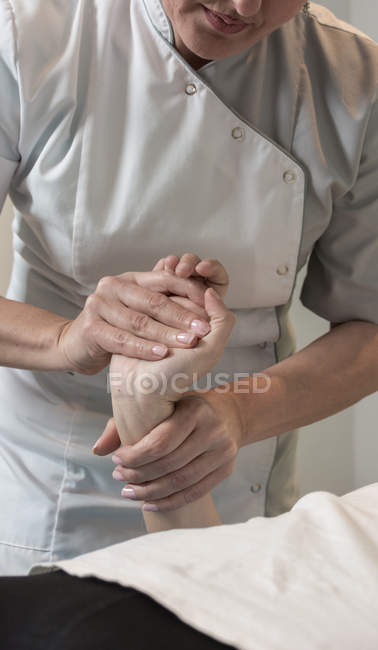 Terapeuta masajeando mano femenina en sala de masajes - foto de stock