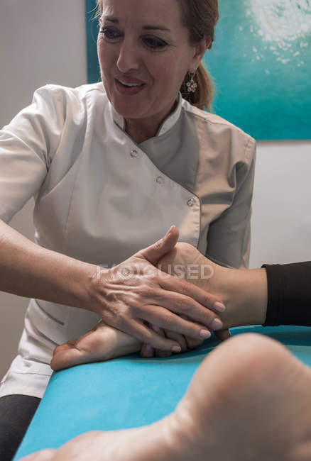 Therapeutin massiert weiblichen Fuß im Massageraum — Stockfoto