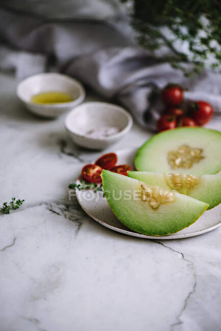 Slices of yummy fruit with seeds lying on plate near cherry tomatoes — Stock Photo