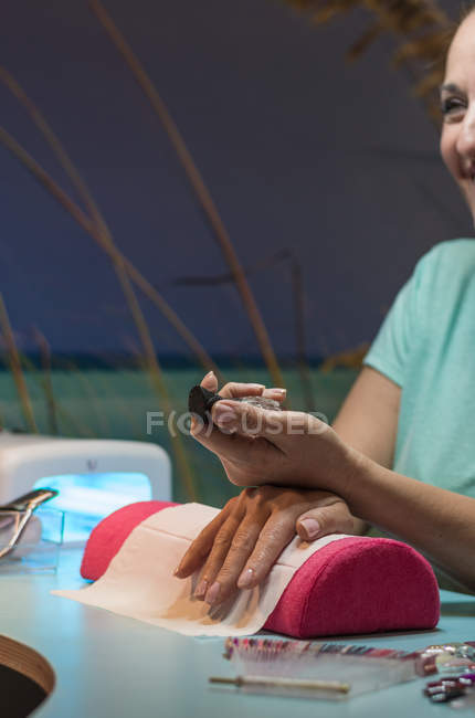 Femme tenant bouteille de vernis à ongles dans un salon de beauté — Photo de stock