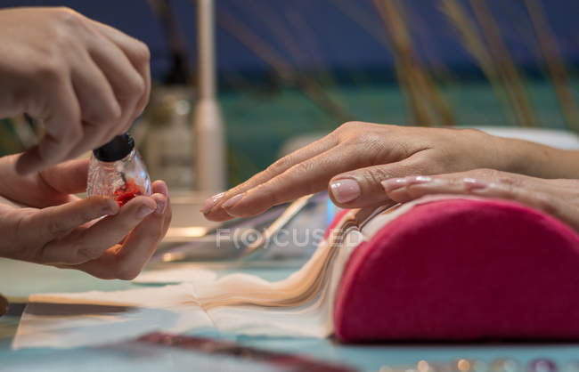 Маникюрша раскрашивает ногти клиента в салоне красоты — стоковое фото