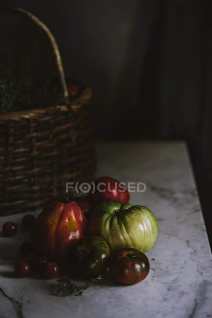 Fresh ripe and unripe tomatoes on white marble tabletop — Stock Photo