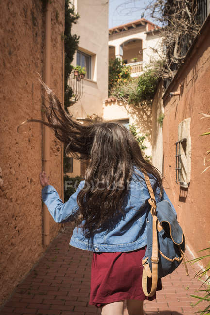Menina com cabelo voador andando na rua ensolarada — Fotografia de Stock