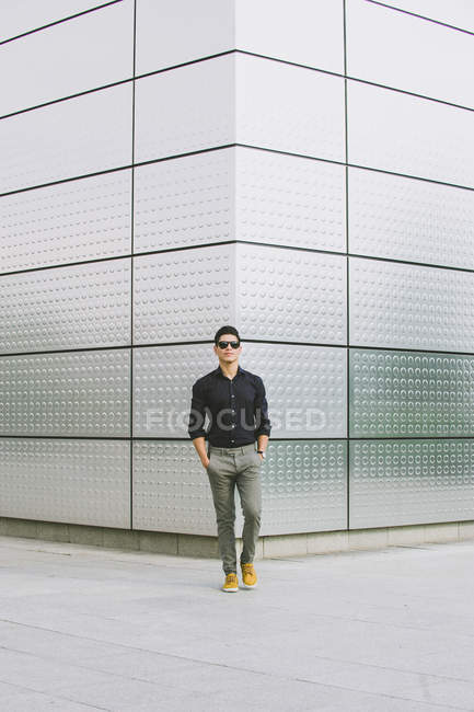 Homem relaxado andando de pé na rua com a mão no bolso e olhando para a câmera — Fotografia de Stock