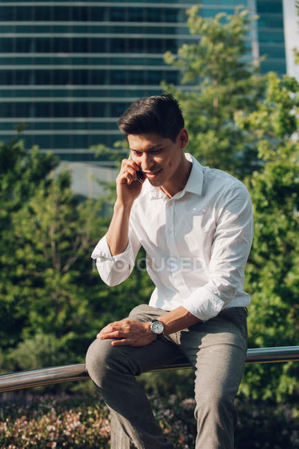 Young elegant businessman talking on phone on railing outdoors — Stock Photo