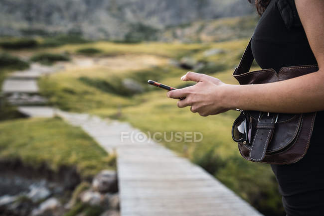 Sezione centrale della donna utilizzando smartphone in natura — Foto stock