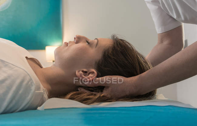 Terapeuta massageando rosto feminino na sala de massagem — Fotografia de Stock