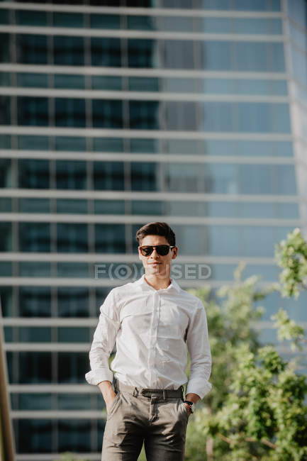 Впевнений молодий бізнесмен стоїть проти сучасної будівлі — стокове фото