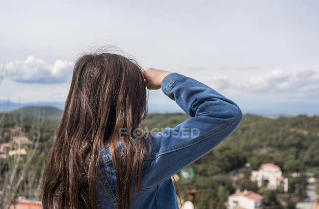 Girl standing on hill and looking at view of town — Stock Photo