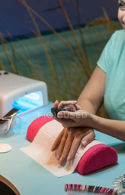 Женщина держит бутылку лака для ногтей в салоне красоты — стоковое фото