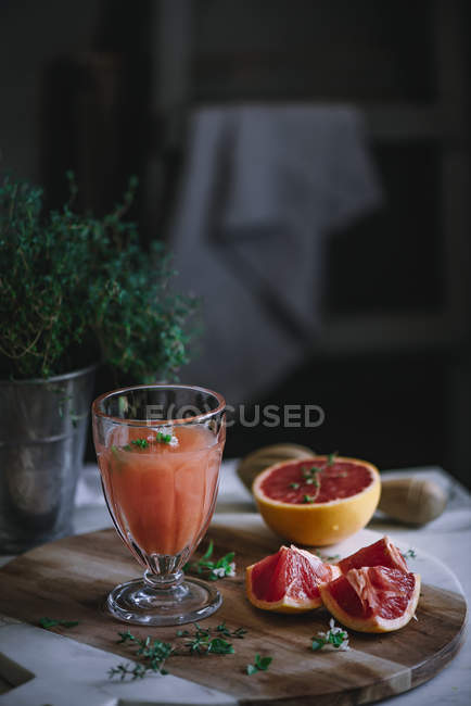 Jus de pamplemousse frais en verre avec ingrédient sur la table de cuisine — Photo de stock