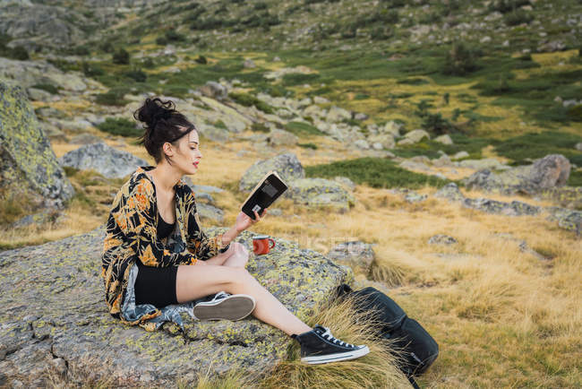 Jeune femme brune lisant un livre sur les pierres en voyage — Photo de stock