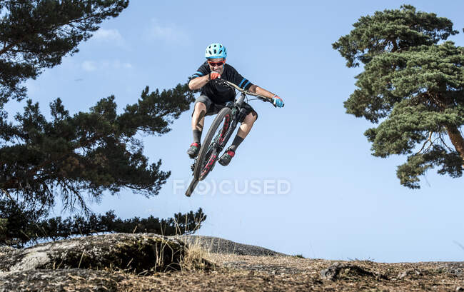 Mountain biker performing jump on bicycle on single track in forest — Stock Photo
