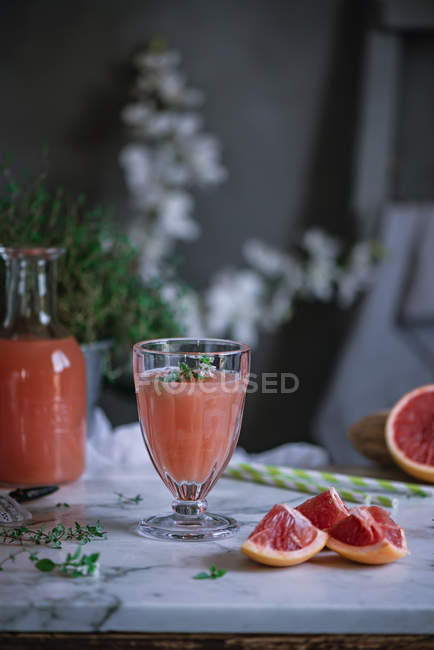 Свежий грейпфрутовый сок в стакане на белом мраморном столе — стоковое фото