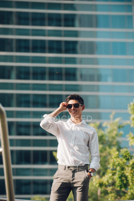 Positive businessman standing against modern building — Stock Photo