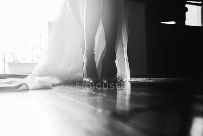 Crop view of bride legs in shoes and floor length white wedding dress in black and white colors — Stock Photo