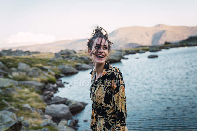 Mulher sensual com cabelo voador rindo na margem do lago em montanhas — Fotografia de Stock