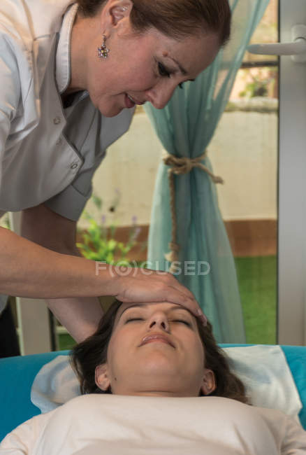 Terapeuta massageando rosto feminino na sala de massagem — Fotografia de Stock