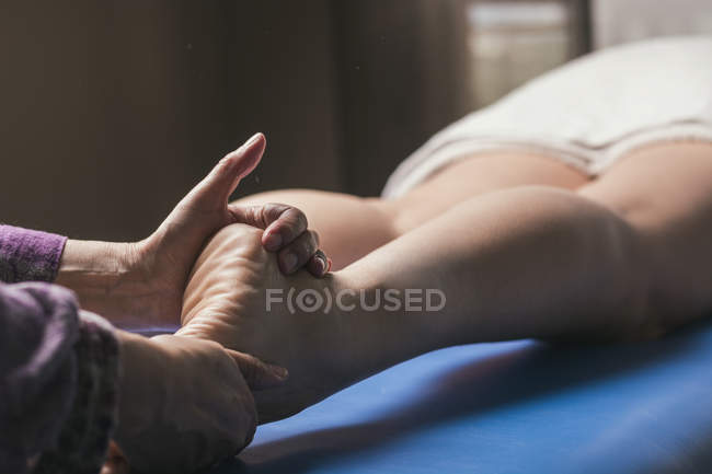 Terapeuta haciendo masaje de reflexología del pie en paciente femenino - foto de stock
