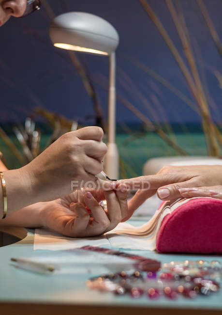 Маникюрша раскрашивает ногти клиента в салоне красоты — стоковое фото