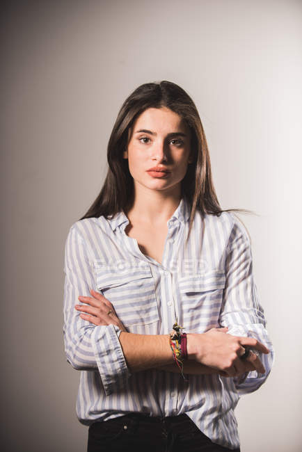 Молода жінка в смугастій сорочці позує на сірому фоні — стокове фото
